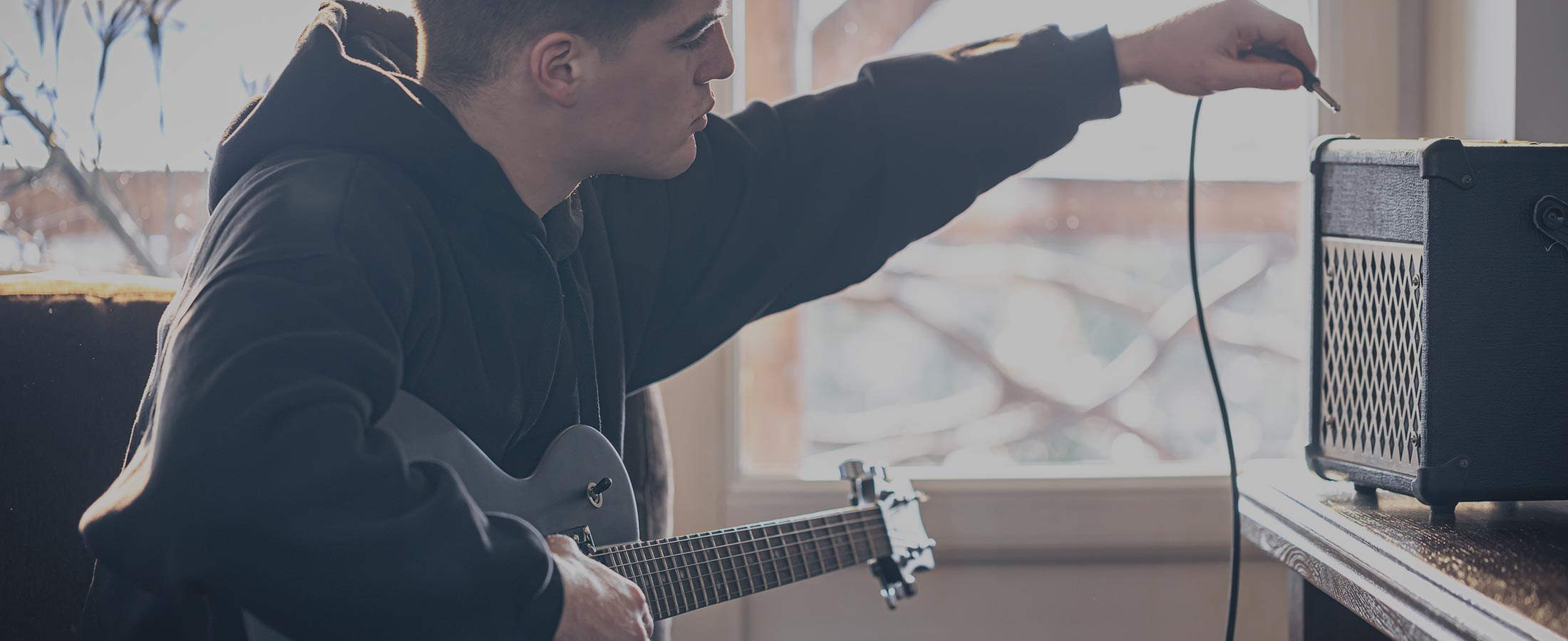 image of young man plugging guitar into amp